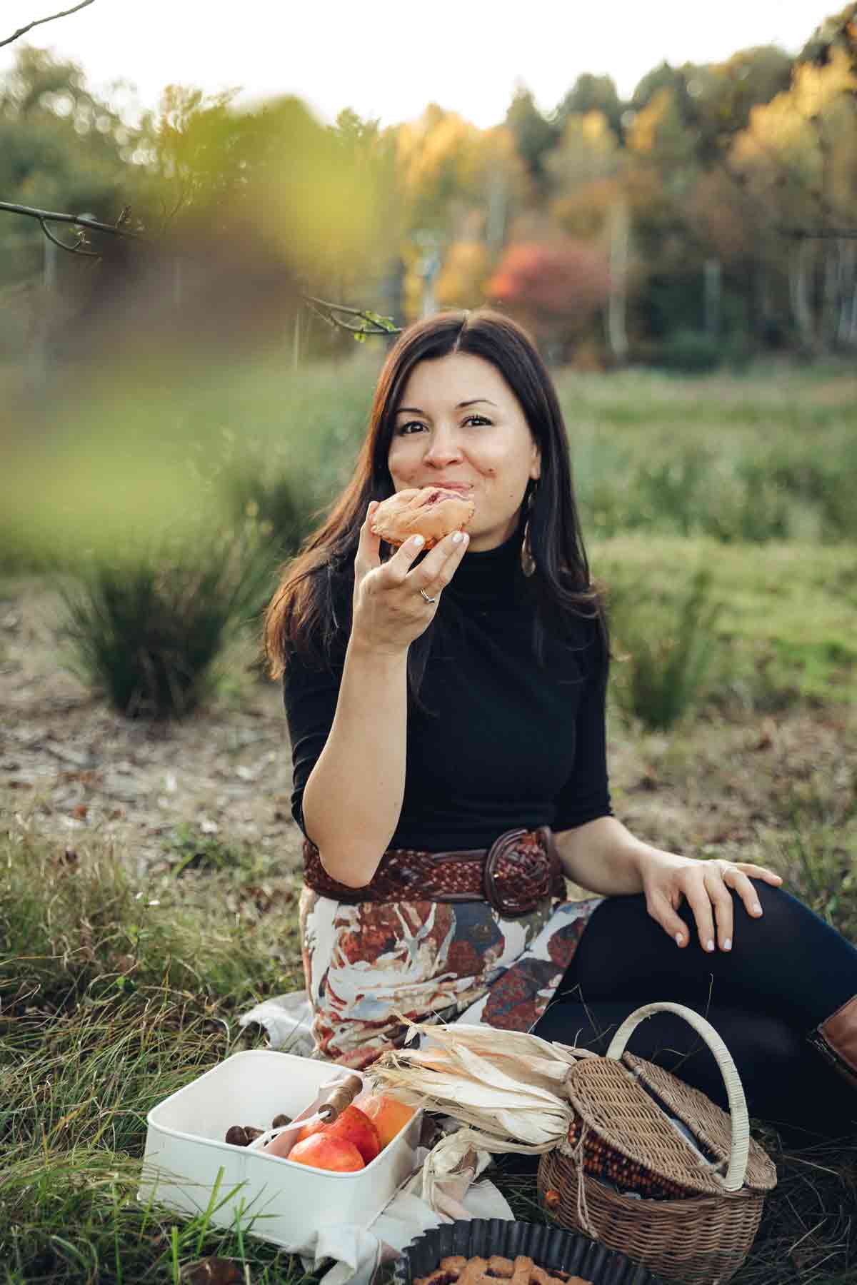 una donna sopra una coperta in mezzo al la natura che mangia